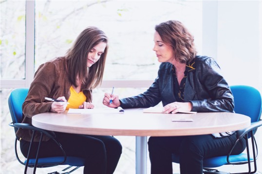 Klarivis team meeting in break room. two team members writing on a notebook